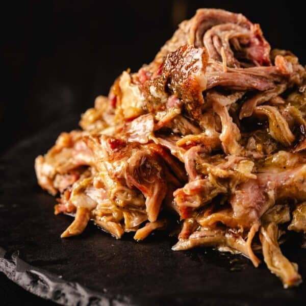 Shredded Chile verde pork piled on a round, black plate.